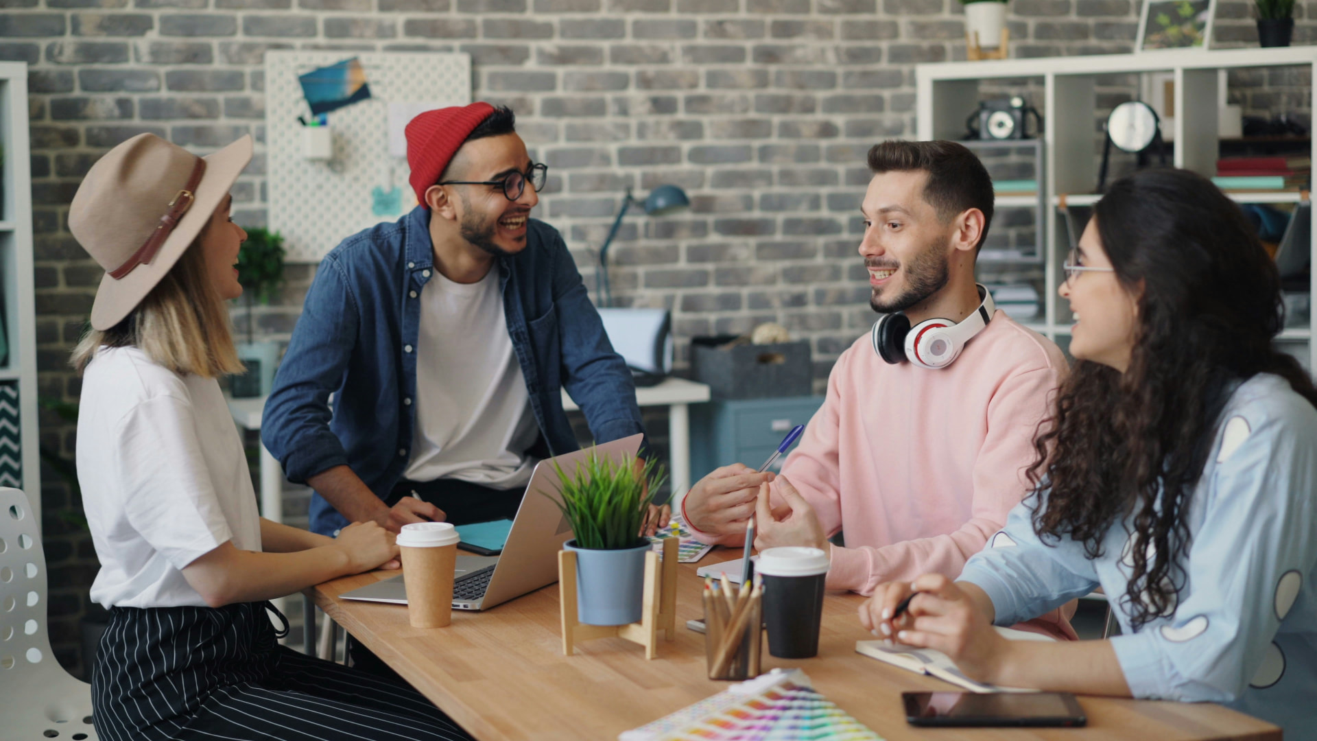 Colleagues in casual business wear talking together around a table in a bright, modern office