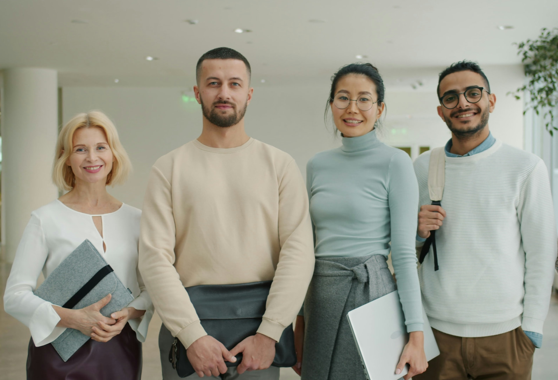 A diverse group of four professionals standing together in a bright, modern office lobby